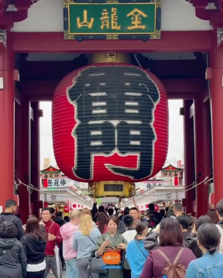 The giant red and black lantern hanging in the Kaminarimon gate at Senso-ji, with visitors passing beneath it