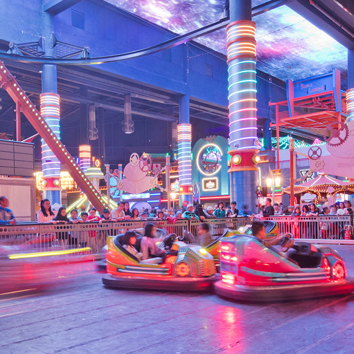 Dodgem cars on the indoor track under a painted galaxy ceiling.