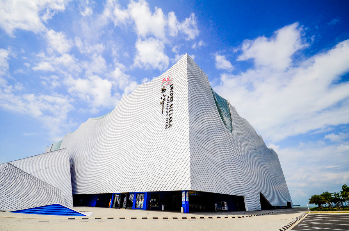 The white faceted exterior of the Encore Melaka theatre against a blue sky.