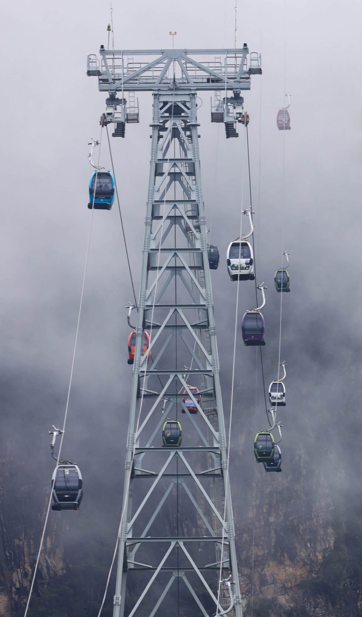 Cable car gondolas climbing the line into thick cloud on the mountainside.