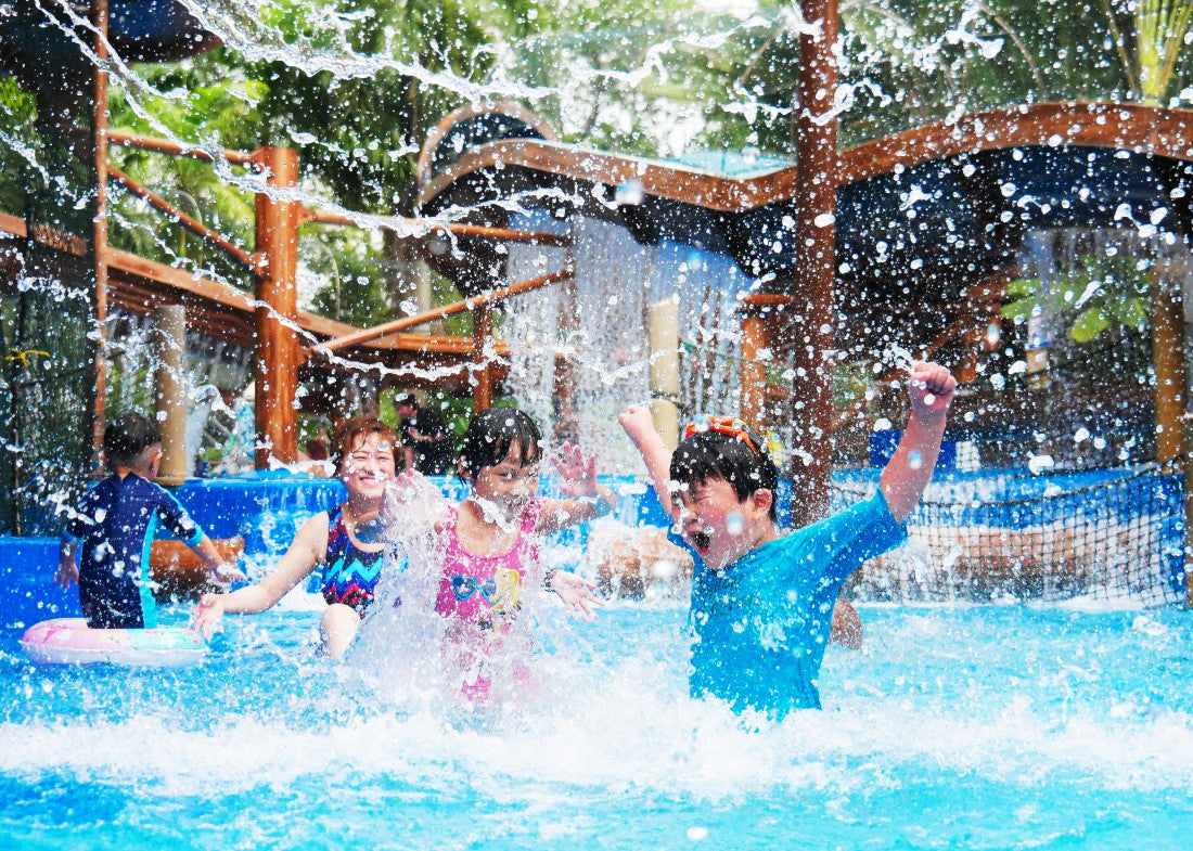 Children playing under falling water in a shallow pool.