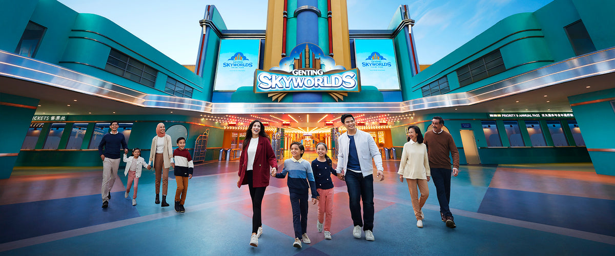 A family walking through the Genting SkyWorlds entrance plaza beneath the park sign.