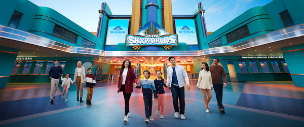A family walking through the Genting SkyWorlds entrance plaza beneath the park sign.
