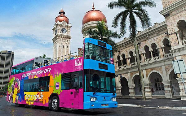 An open-top double-decker sightseeing bus outside the Sultan Abdul Samad Building.