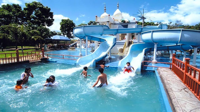 Swimmers in a wave pool at A'Famosa water park, with white domed towers behind.
