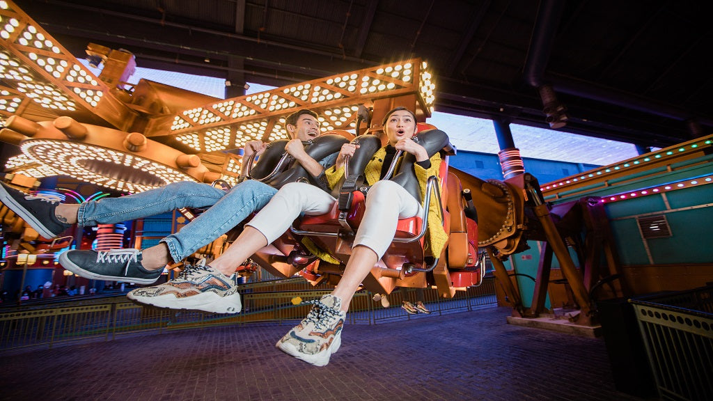 Two riders flung sideways on a spinning ride, legs in the air.