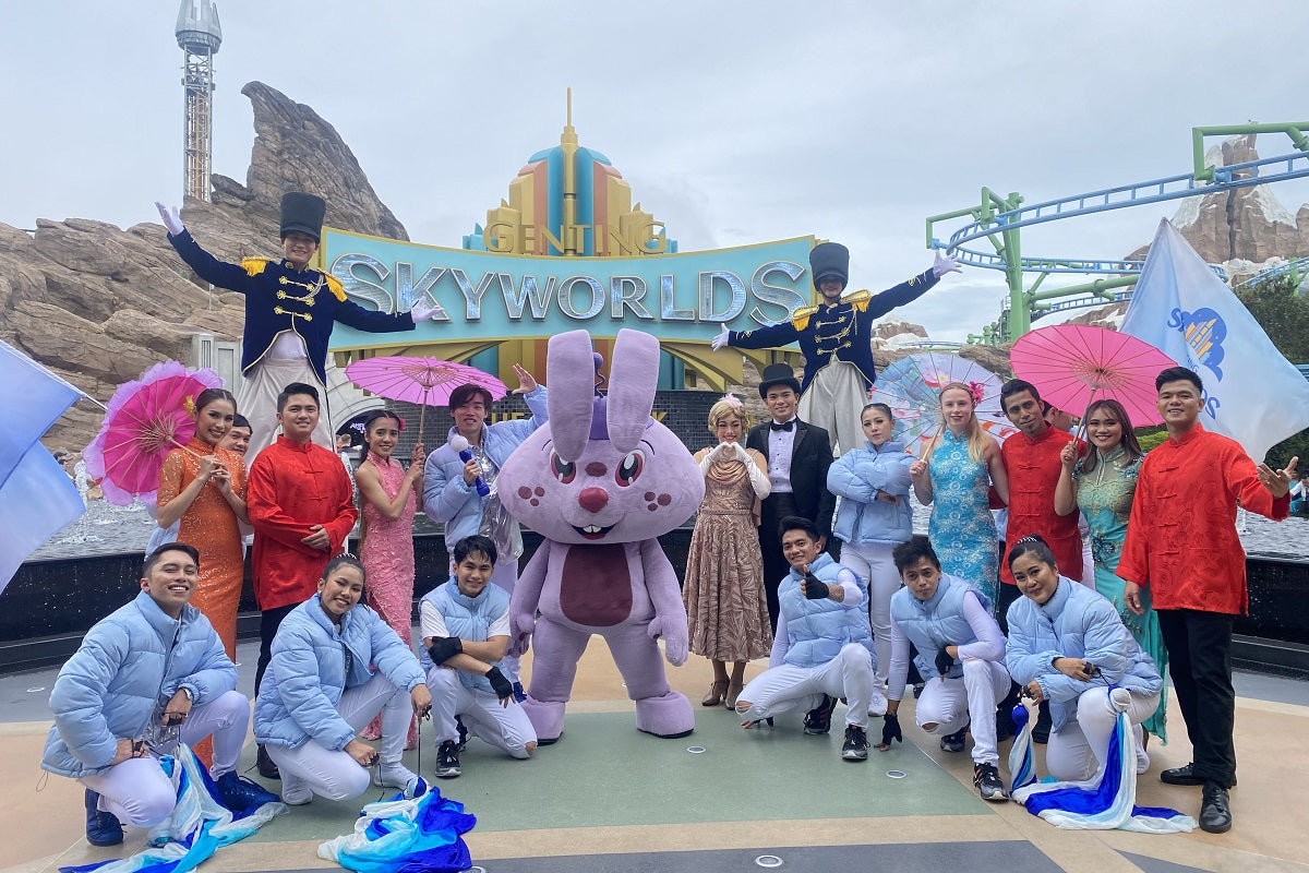 A large costumed group posing at the SkyWorlds sign with a rabbit mascot.