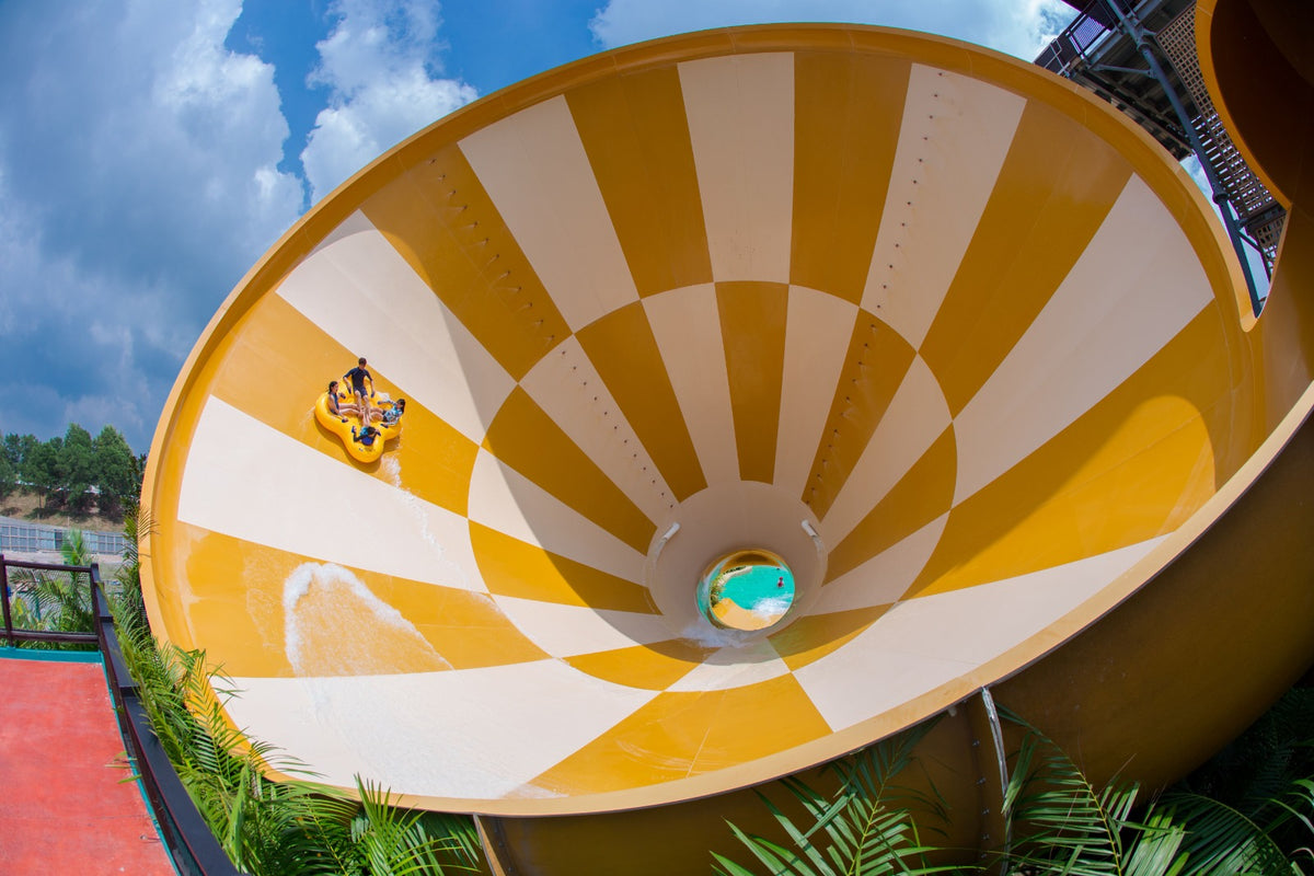Looking down into a large yellow and white funnel slide with a raft sliding through it.