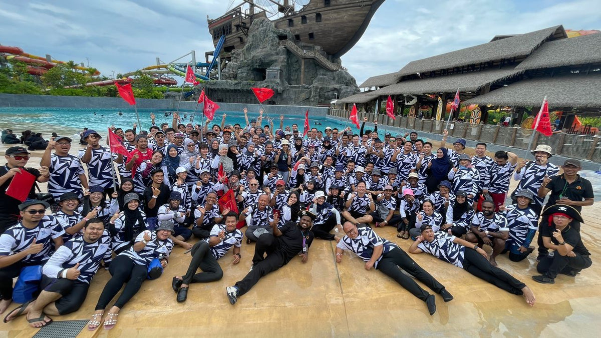 A large group in patterned shirts posed on the poolside beside the pirate ship.
