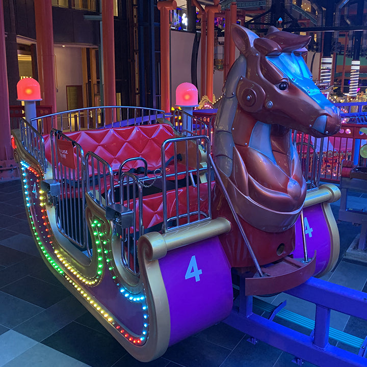 A horse-drawn carriage ride car, outlined in coloured lights.