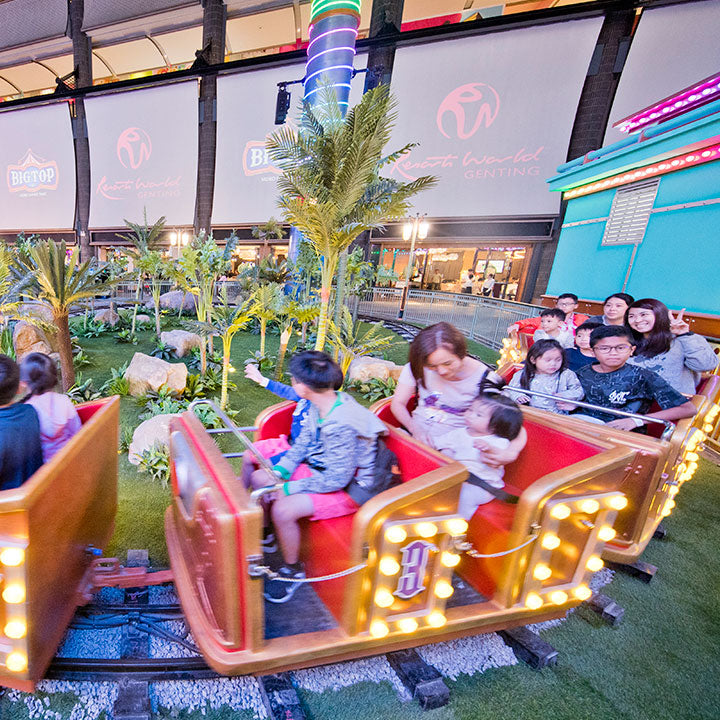 Families riding a small train past planting inside First World Plaza.