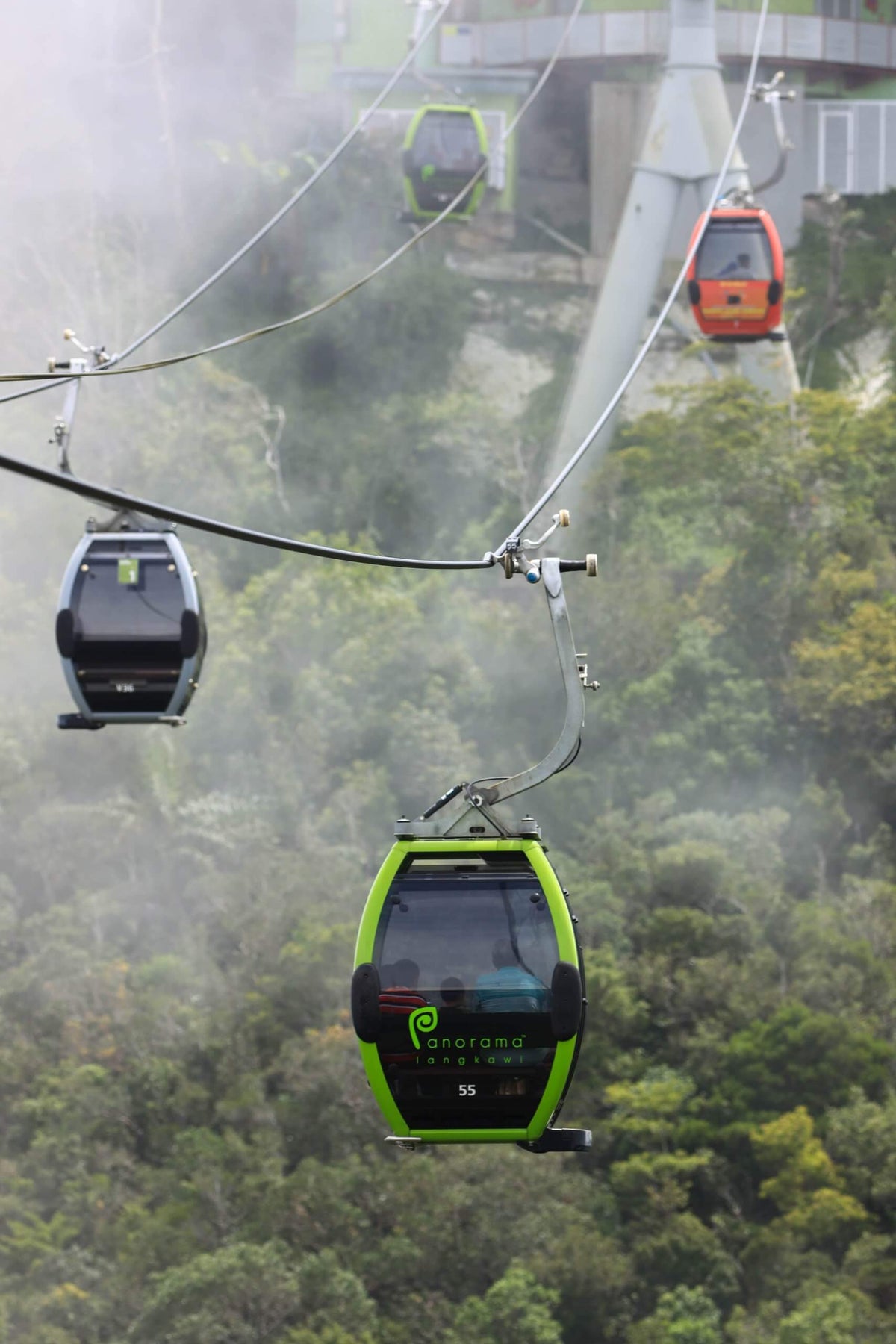 Gondolas crossing in mist, one climbing and one descending.