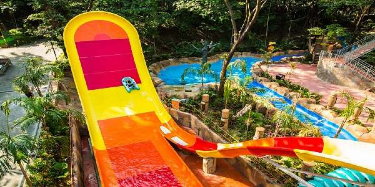 A wide orange and pink drop slide seen from above, with the park beyond.