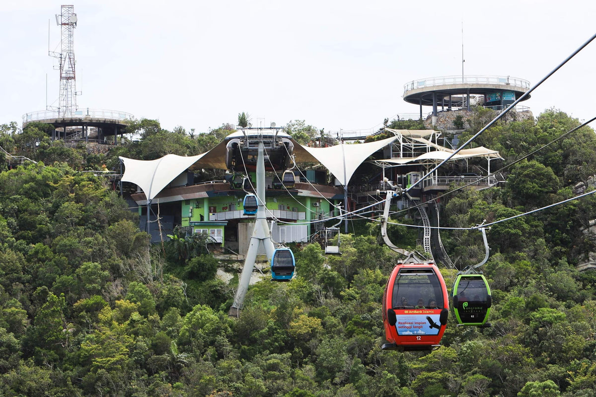 The summit station's white tented roofs seen from above, with gondolas on the line below.