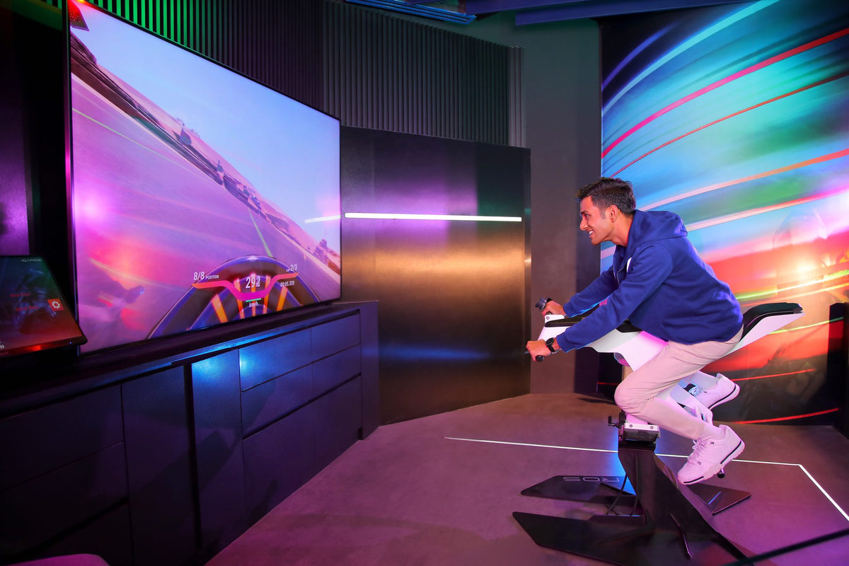 A visitor leaning into a motorbike riding simulator at Petrosains, racing on a large screen under neon light.