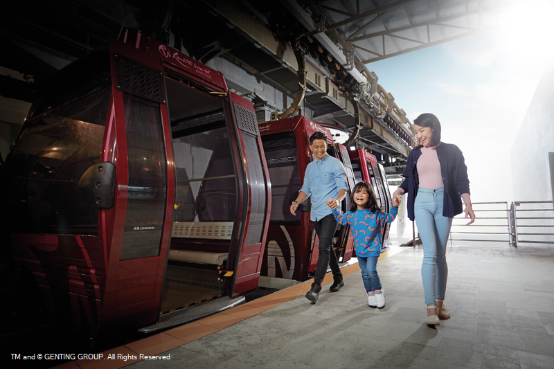 A family walking past an open red Awana SkyWay gondola at the boarding platform.