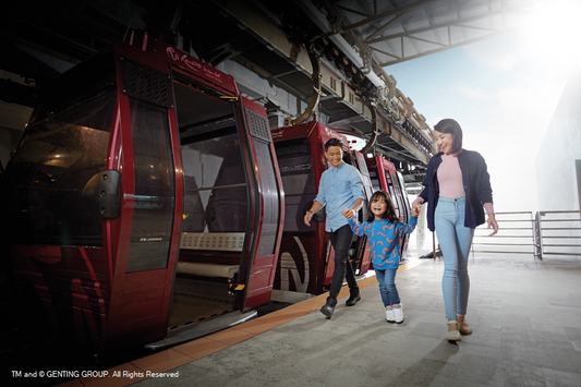 A family walking past an open red Awana SkyWay gondola at the boarding platform.