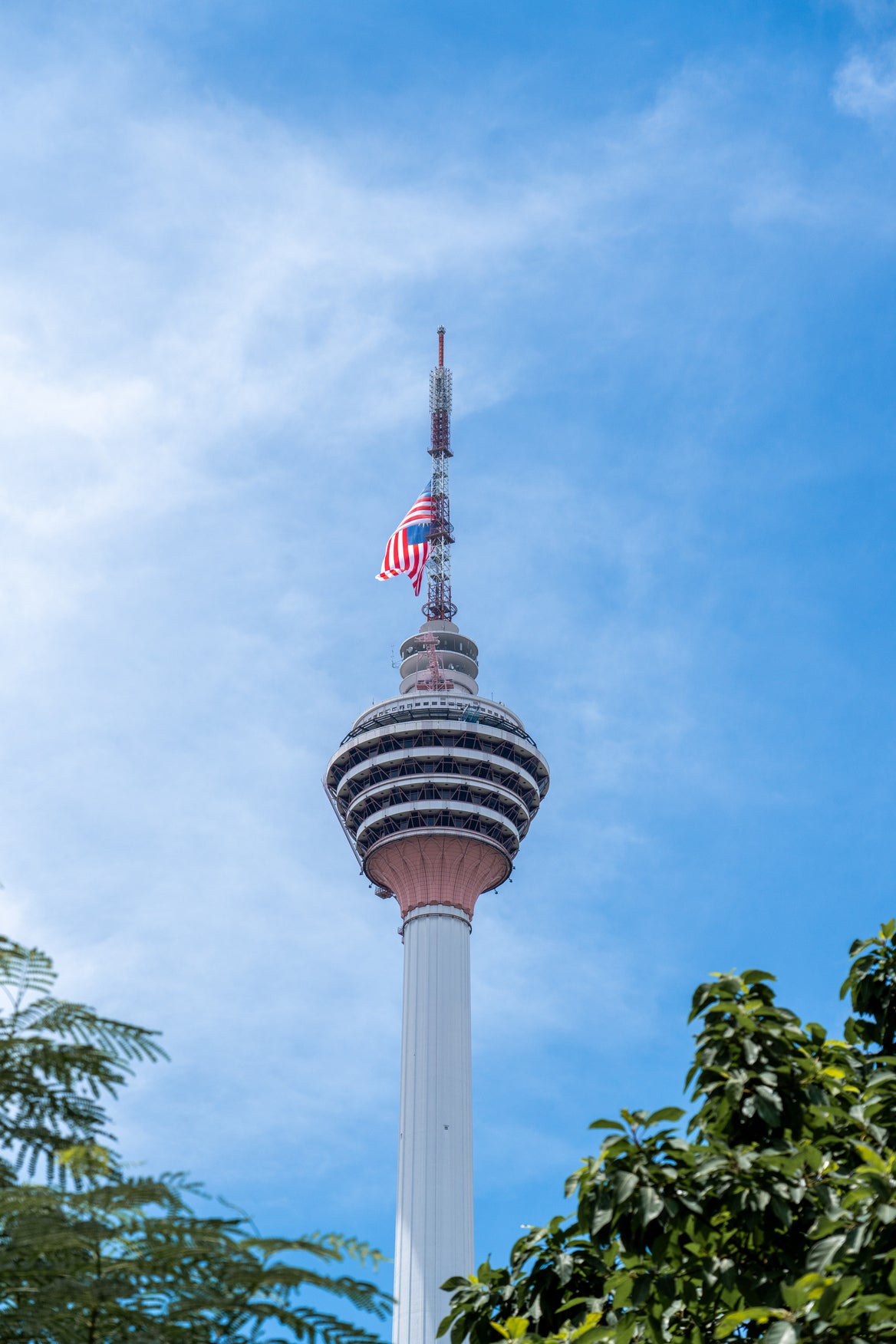 KL Tower's head and mast from below, the Malaysian flag flying at the top.