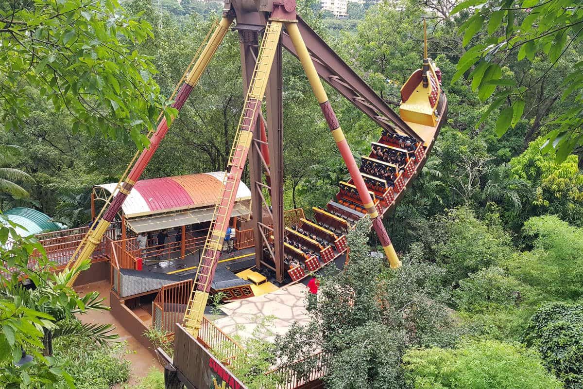 A large pirate ship swing ride at rest above the trees.