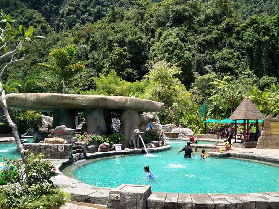 A turquoise hot spring pool set among limestone rock and jungle.