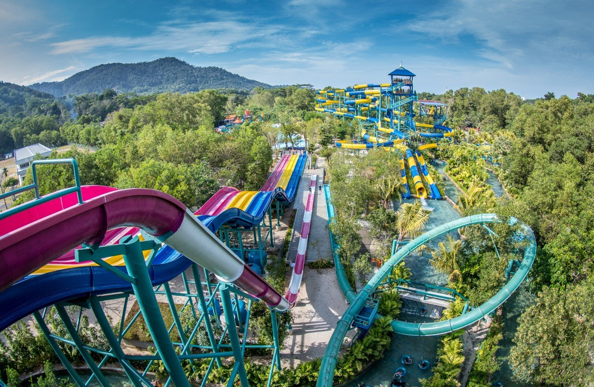 Aerial view of ESCAPE Penang, its waterslides winding down a forested hillside with mountains behind.