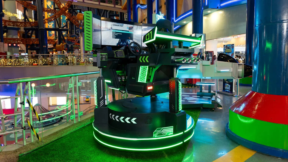 A green neon-lit simulator ride standing on an astroturf floor inside the mall.