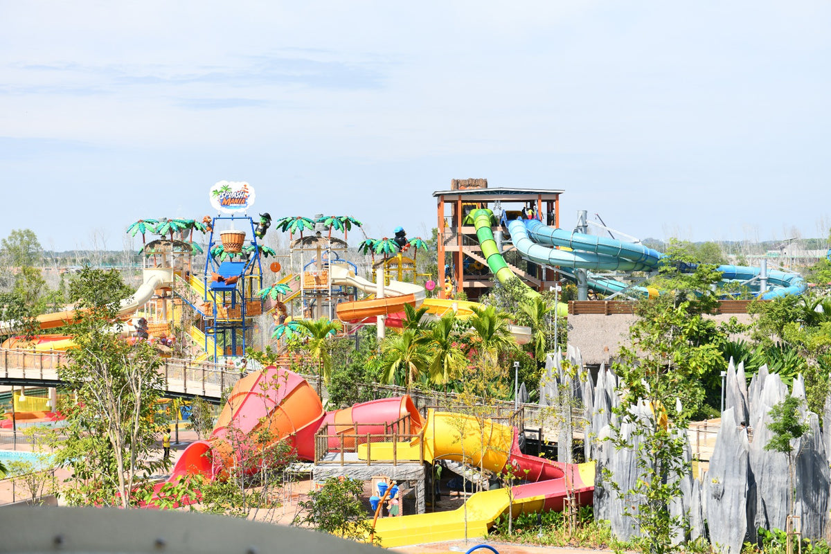 Wide view of the park's slide towers and themed structures among young planting.