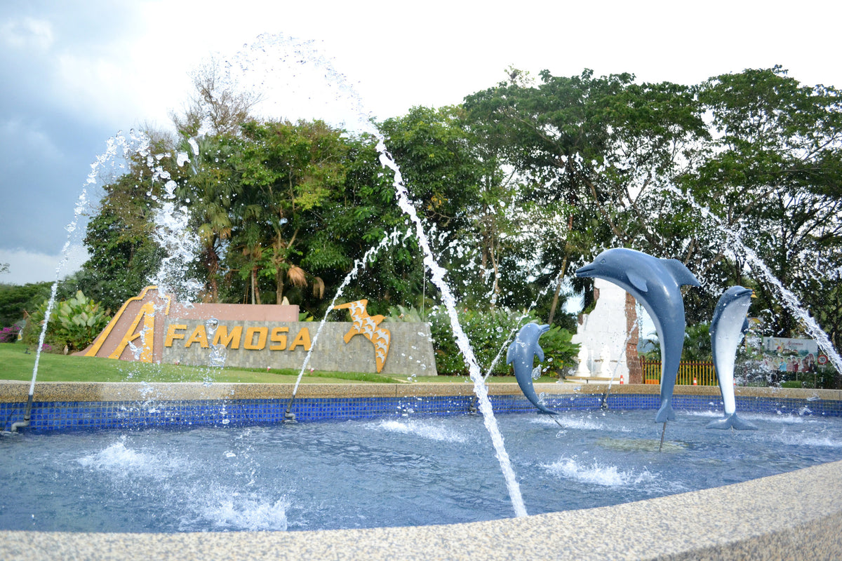 A fountain with leaping dolphin sculptures in front of the A'Famosa sign, framed by trees.