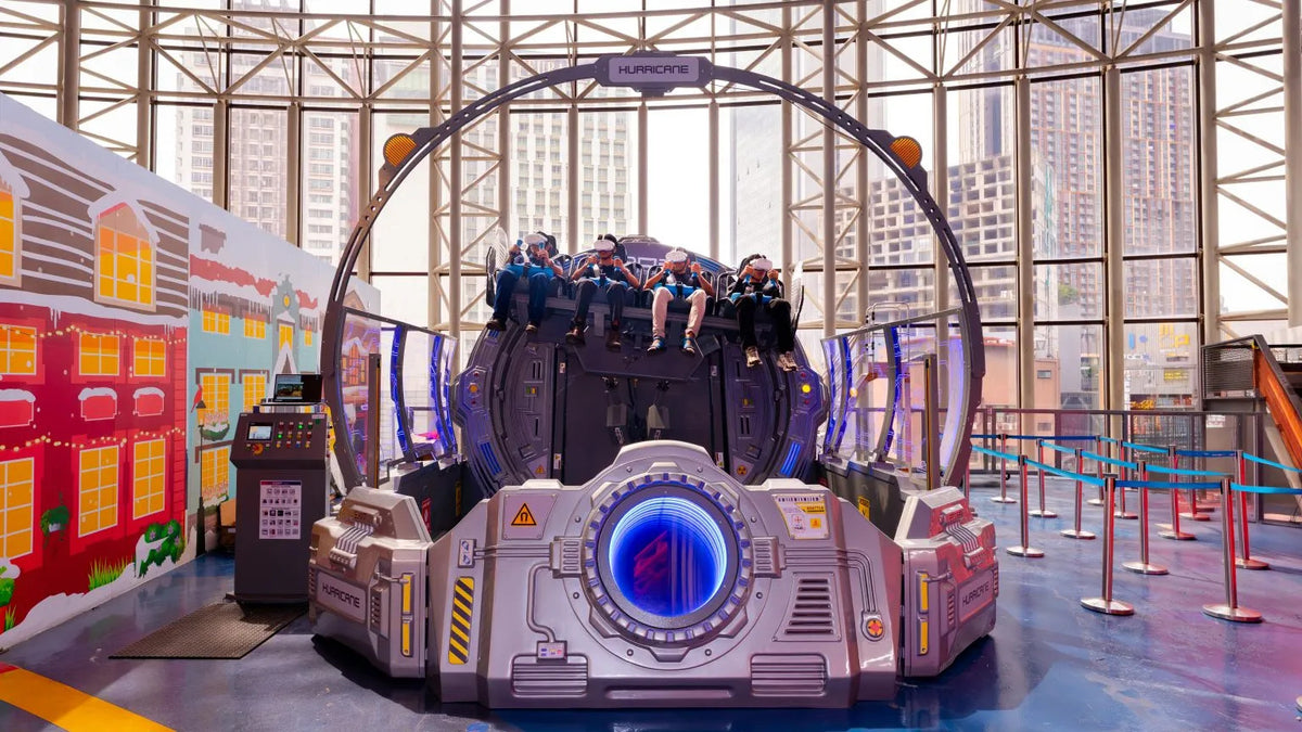 A domed spinning ride beside painted house facades, with the city visible through the glass wall.