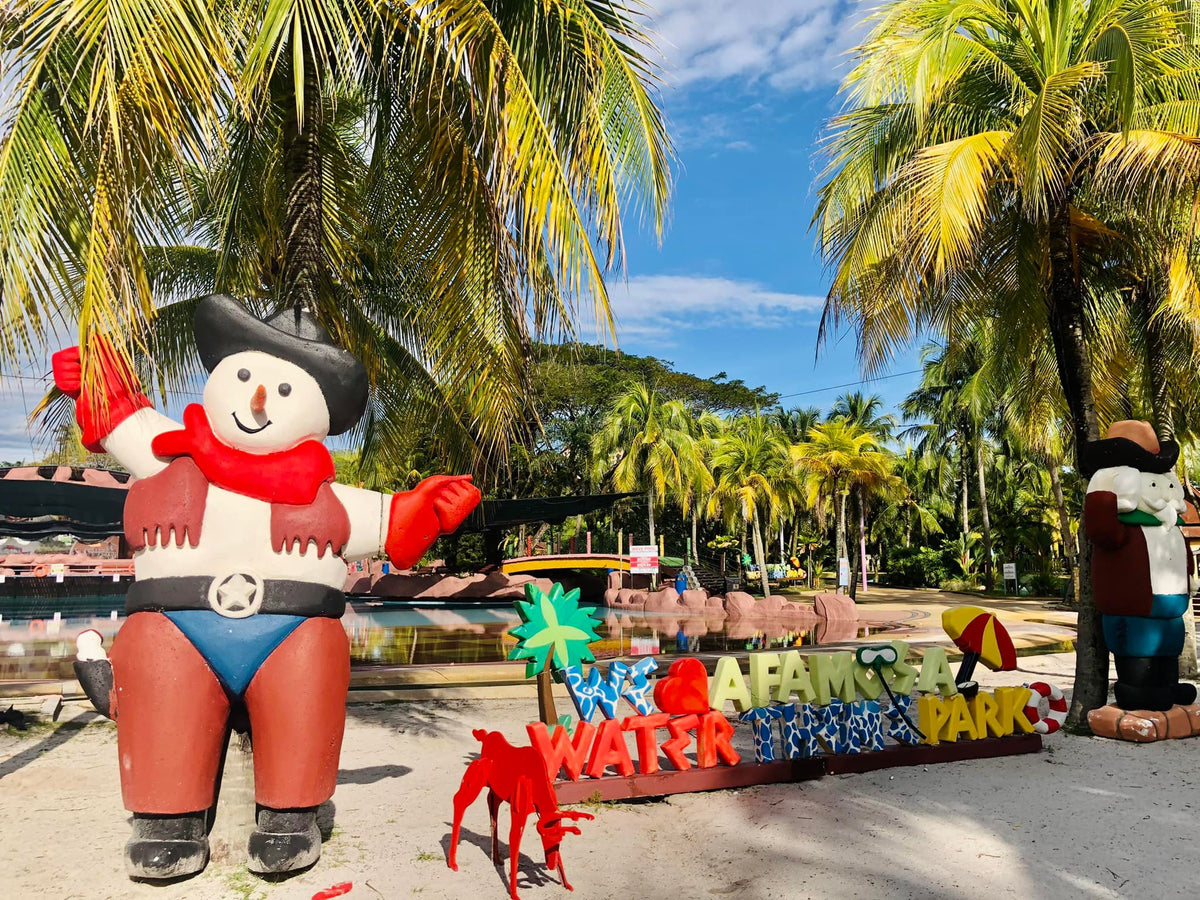 Inflatable pirate figures beside the A'Famosa Water Park entrance sign under palm trees.