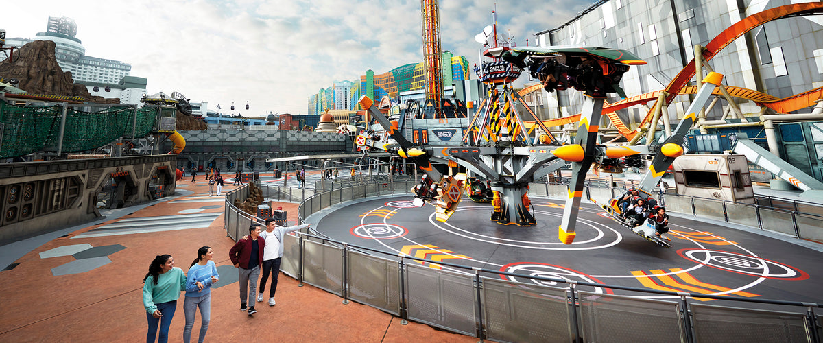 A spinning aerial ride in the Robots zone, with visitors watching from the rail.