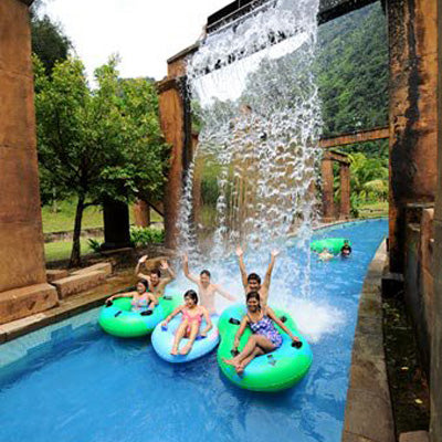 Riders in green rings cheering as water pours over them from the structure above.