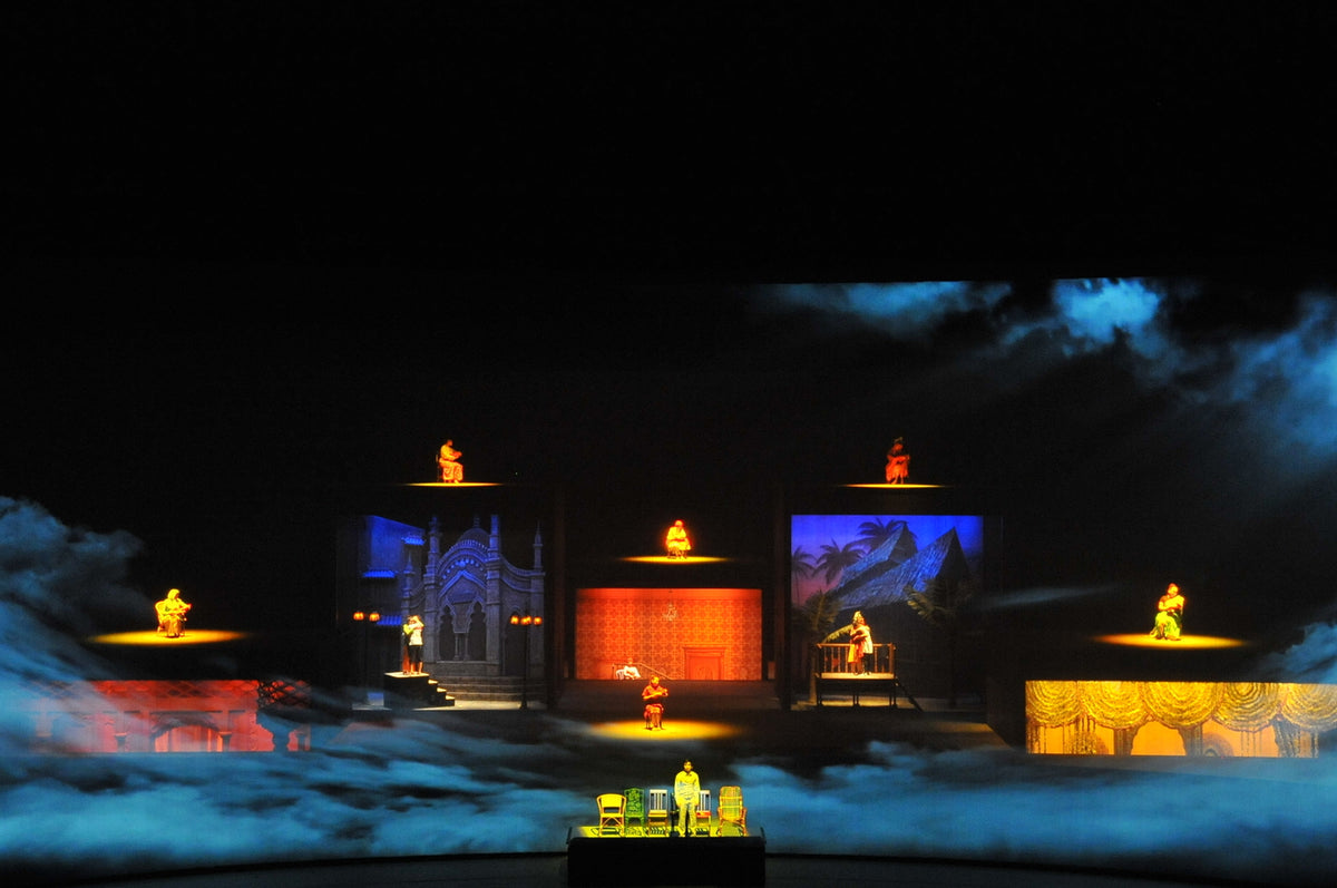 A multi-level stage set lit in orange and blue, with performers in separate lit alcoves.