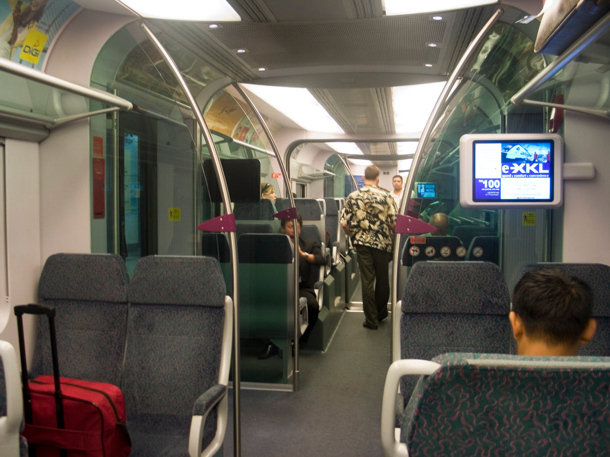 The interior of a KLIA Ekspres carriage, passengers seated with luggage beside them.