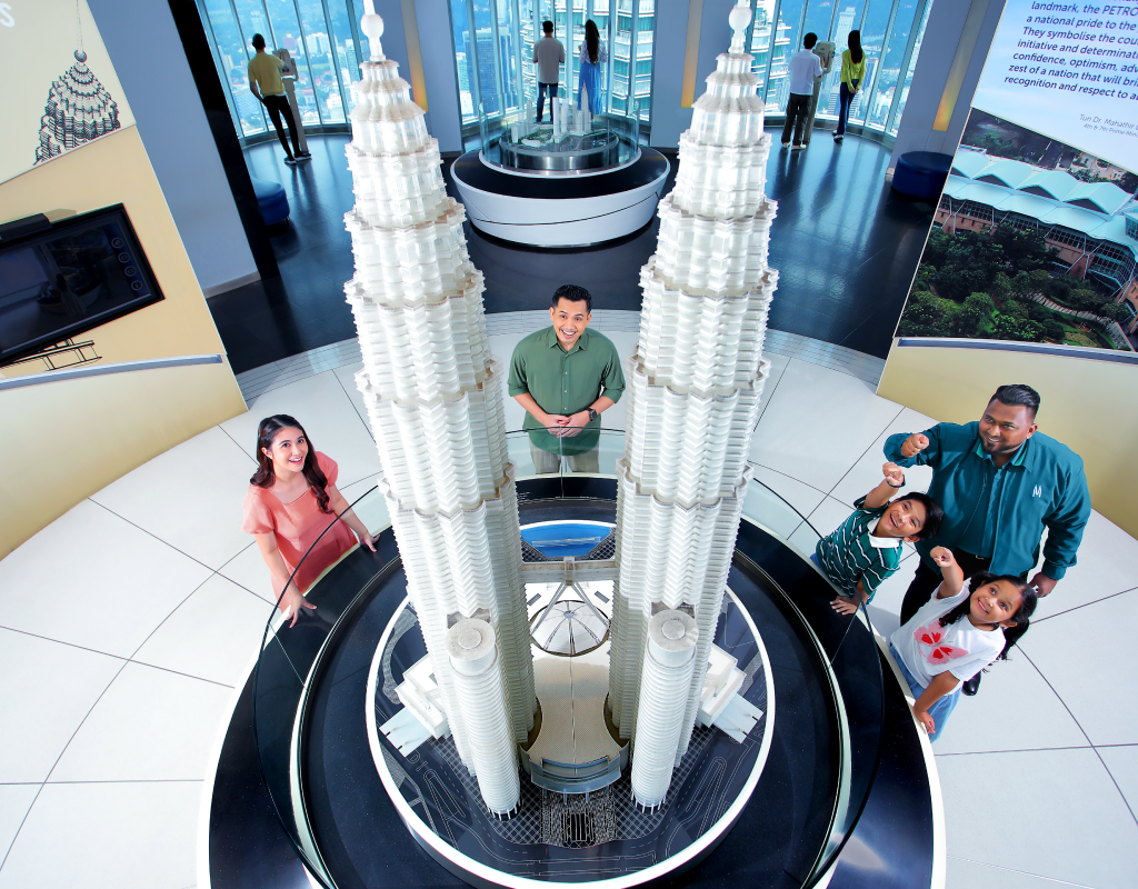 Visitors posing around a scale model of the Petronas Twin Towers in the exhibition area.