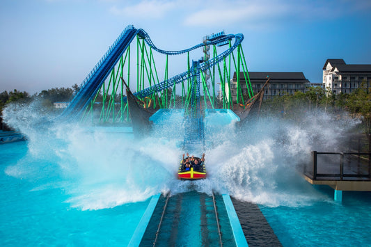 A water coaster boat hitting the splash-down at speed, throwing spray across the track.