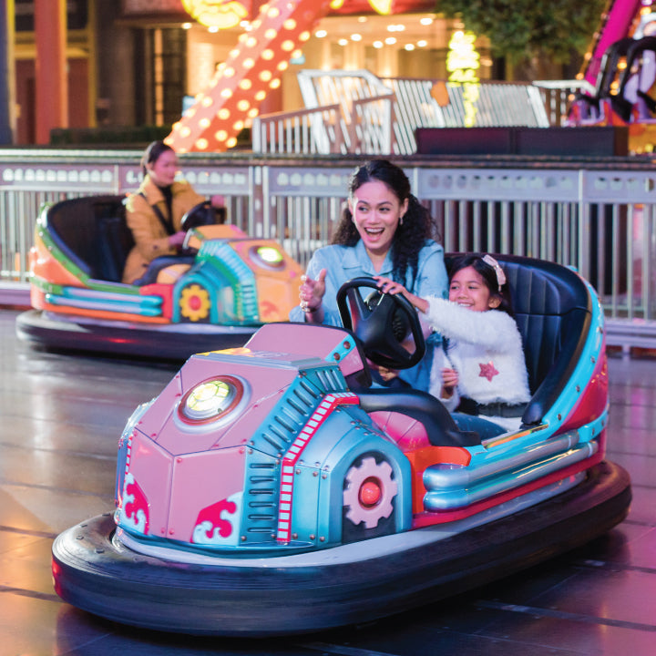 A woman and child laughing in a pink dodgem car.