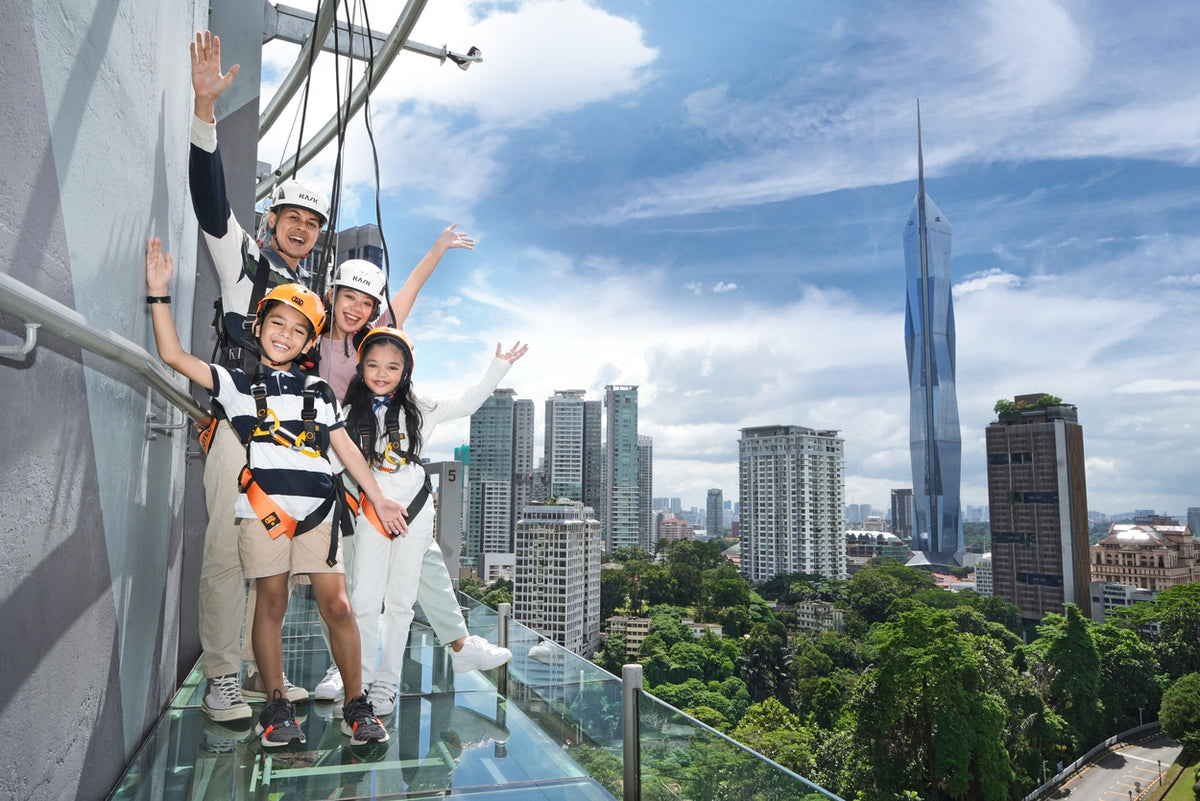 A family in harnesses on the open Sky Deck, the city and skyscrapers behind them.