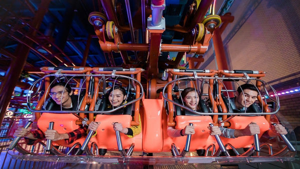 Riders strapped into a red indoor roller coaster car, mid-ride.