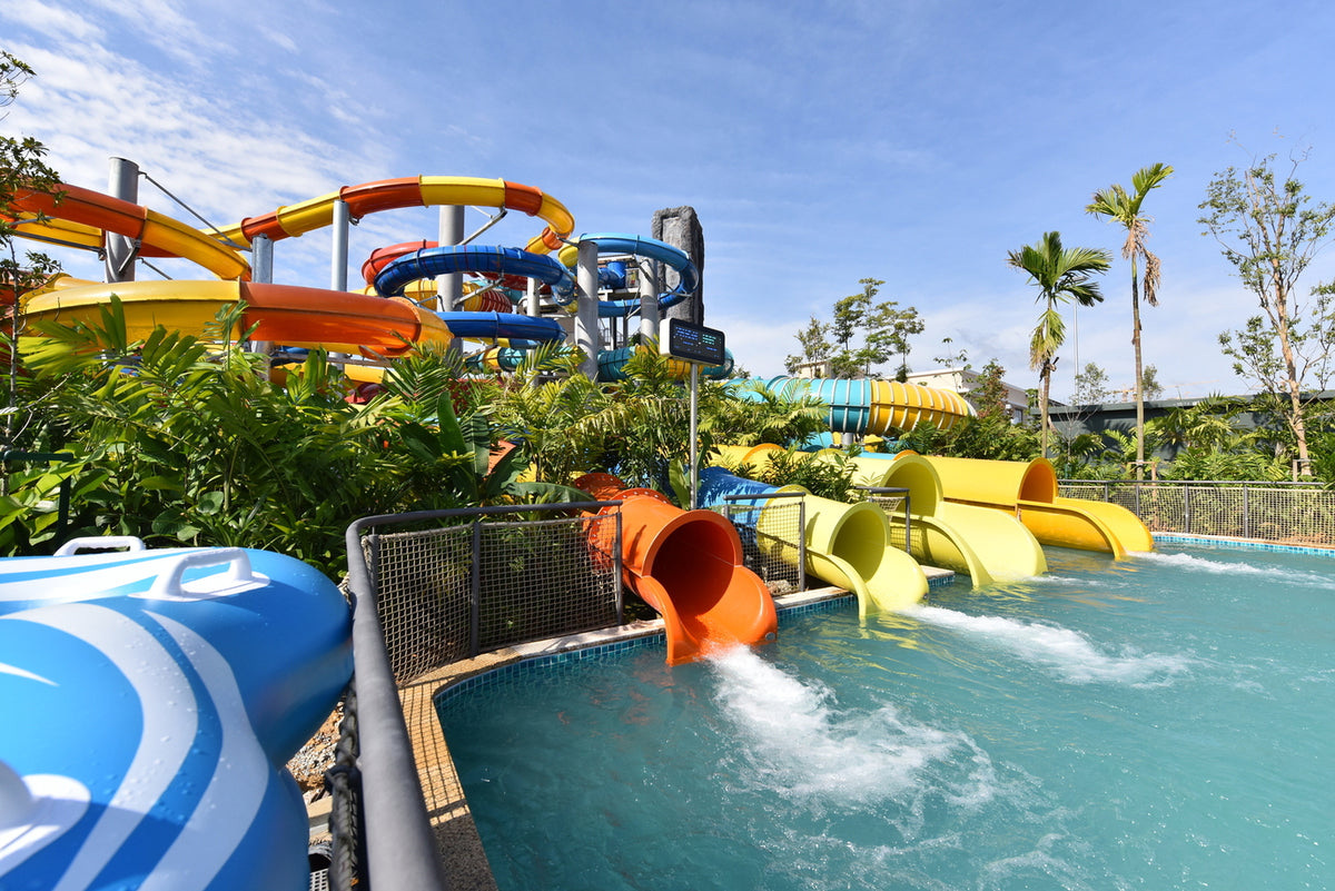 Orange and yellow slide exits emptying into a pool below a tangle of slide towers.