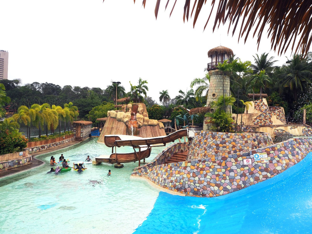 The wave pool with its lighthouse and shipwreck theming, seen from under a thatched roof.