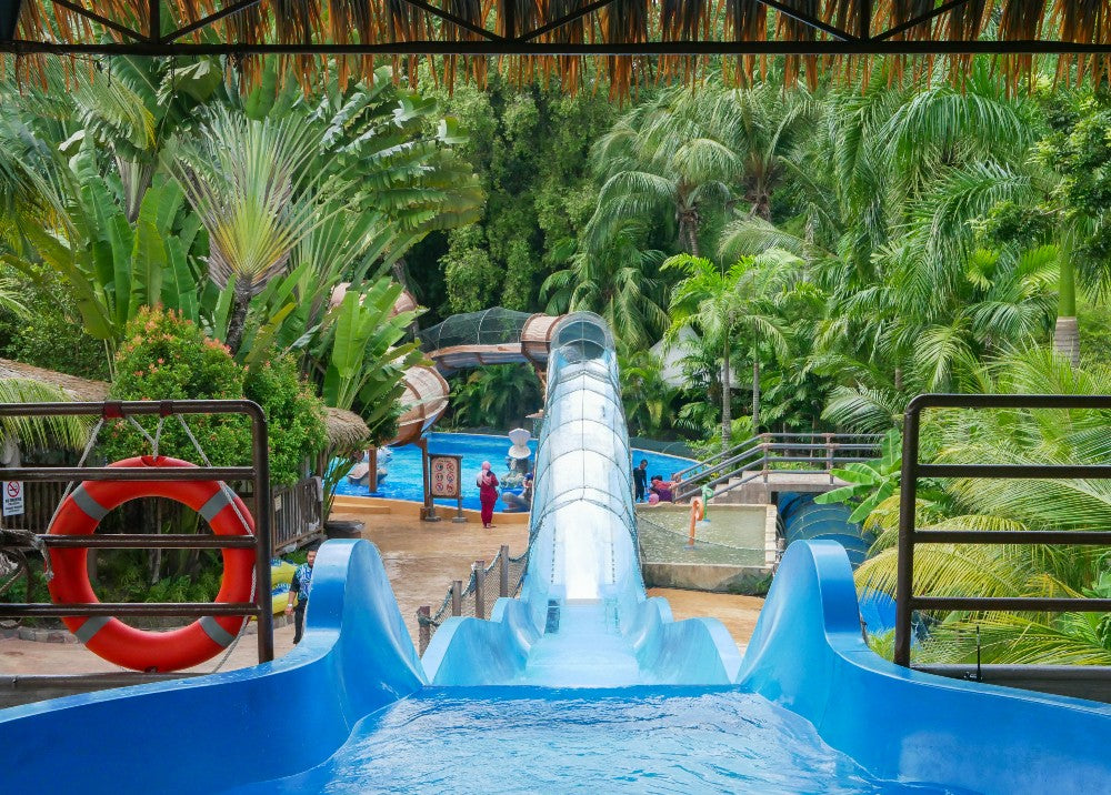 Looking down a wide blue slide towards the park, a lifebuoy hanging on the rail.