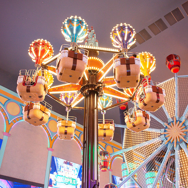 A balloon-themed aerial carousel lit up beneath the indoor ceiling.