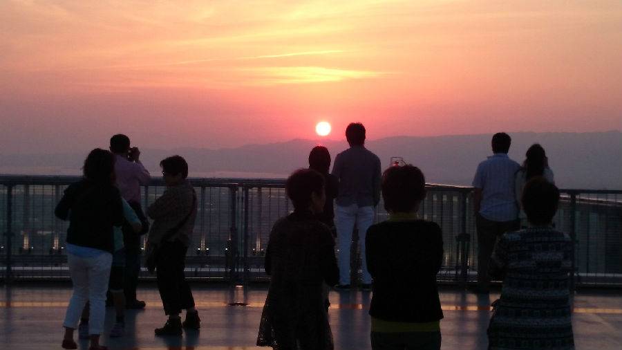 Visitors silhouetted against the sunset on the open-air deck at HARUKAS 300