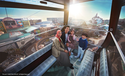 The view from inside a glass-floor gondola, a family seated as the Genting Highlands resort and hills spread out below.