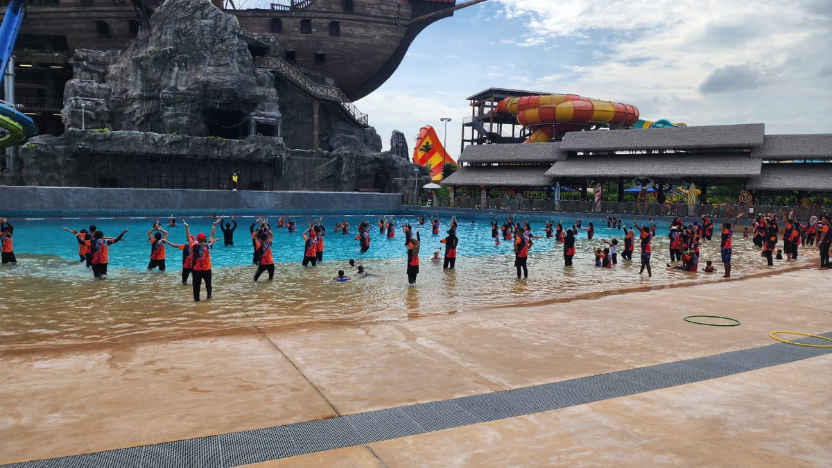 A large group in red shirts standing in the wave pool during an organised session.