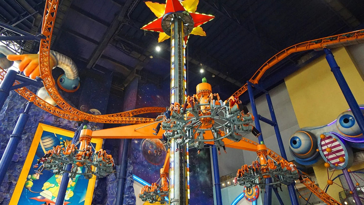 A star-topped tower ride with the roller coaster track curving overhead.