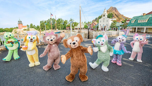 Duffy the Disney Bear and friends greeting guests on the waterfront at Tokyo DisneySea, with a striped lighthouse and moored sailing ships behind.
