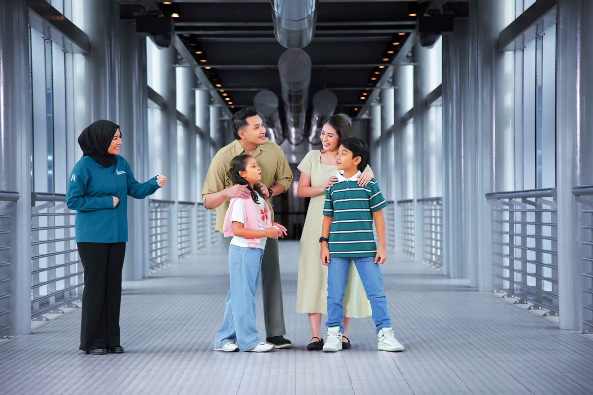 A guide welcoming a family of four onto the Skybridge.