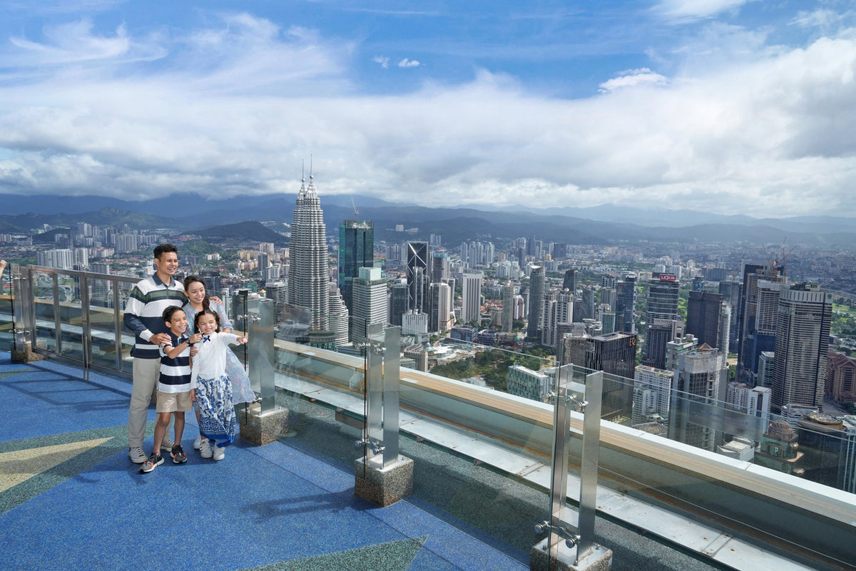 A family posing on the Sky Deck with the Petronas Twin Towers in the distance.